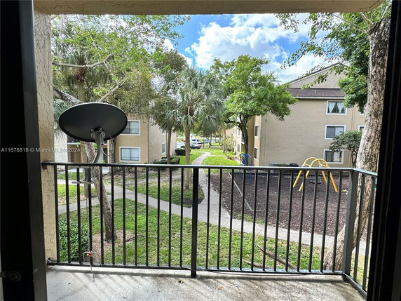 View from a balcony showing apartment buildings, a satellite dish, and an outdoor play area with slides.