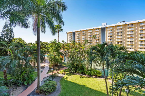 View of a multi-story apartment building surrounded by palm trees.