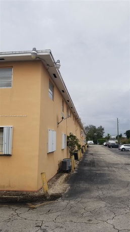 Side view of a two-story building with a parking area.