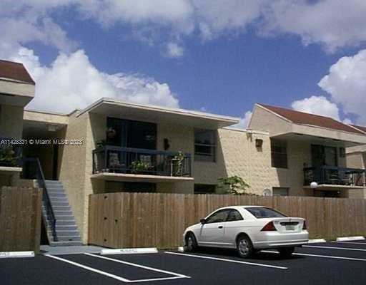 Outdoor parking area in front of a two-story building with balconies.