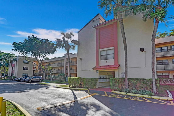 Front view of a multi-story residential building with parking area.