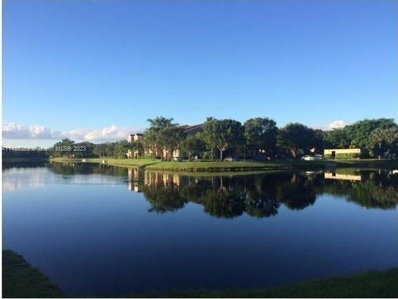 View of buildings and trees reflected in a calm lake.
