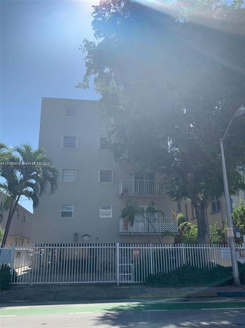 Front view of a multi-story building with balconies and a gated entrance.