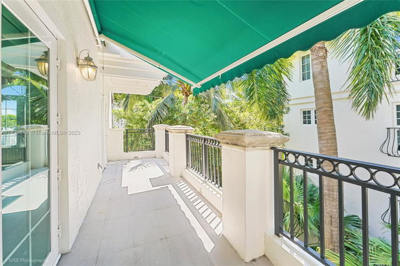Balcony view with greenery and adjacent building.