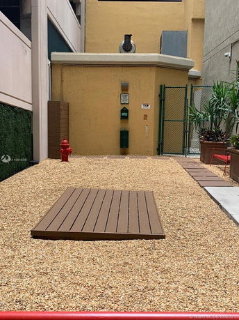 Area with gravel surface, red fire hydrant, and a small structure with a pipe protruding from the top.