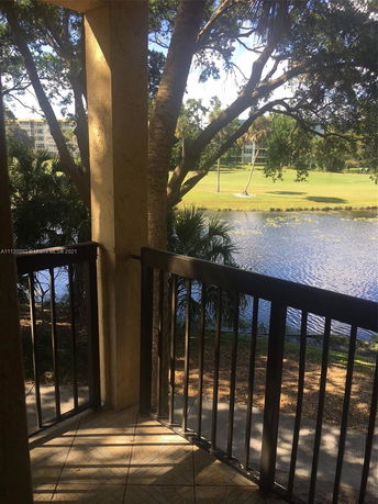 View from a balcony overlooking trees, a small lake, and grassy area.