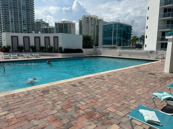 Outdoor swimming pool with lounge chairs and surrounding buildings.