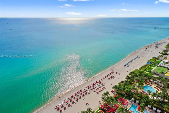 Aerial view of a beach with red umbrellas and a turquoise ocean.