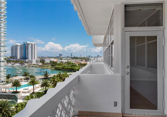 Panoramic view from a balcony overlooking water and cityscape with modern high-rise buildings.