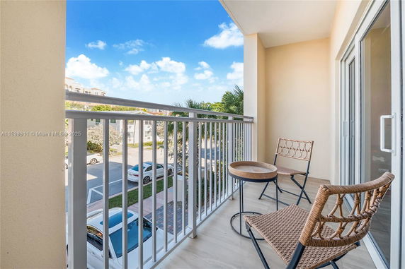 Balcony view showing outdoor surroundings with chairs and table.
