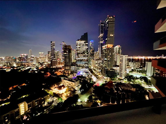 Nighttime panoramic view of a city skyline with tall buildings and lights.