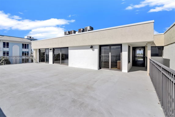Flat rooftop with sliding glass doors and railings.