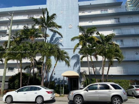 Front view of a multi-story building with balconies and palm trees.
