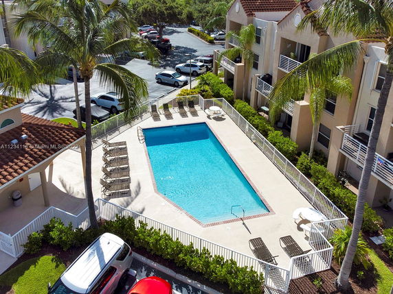 Outdoor swimming pool area with lounge chairs and surrounding buildings.