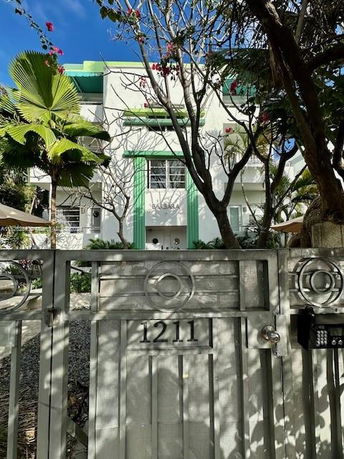 Front view of a multi-story building with green accents and a gated entrance.