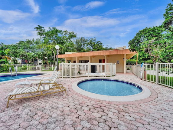 Outdoor swimming pool area with sun loungers and a small round pool.
