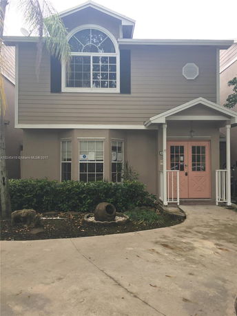 Front view of a two-story house with arched window and porch.