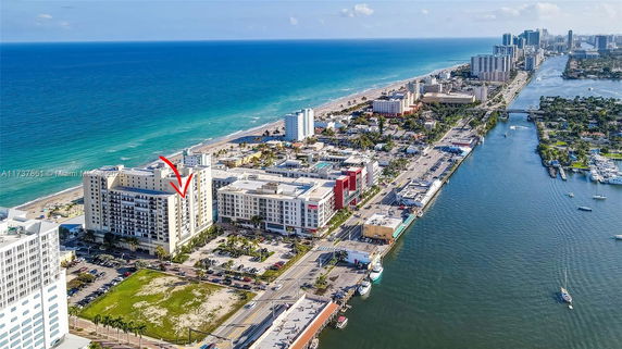 Aerial view of a coastal cityscape with high-rise buildings, a beach, and a waterway.