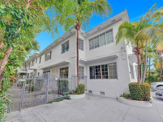 Front view of a two-story house with a gated entrance and white exterior.