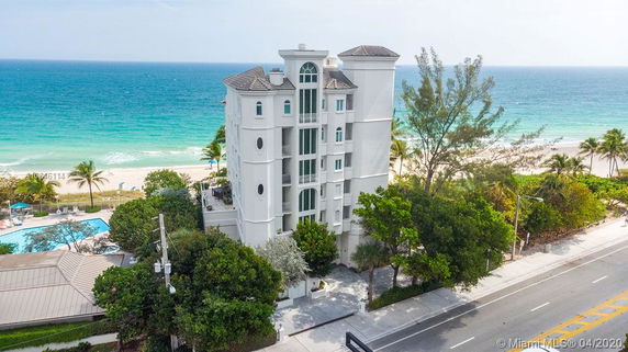 Front view of a multi-story white building by the beach.