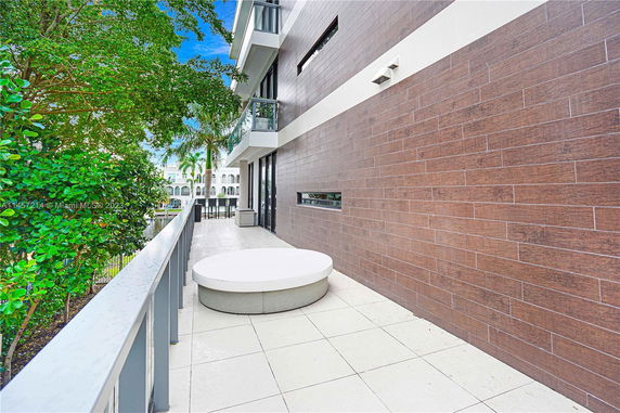Outdoor view from a balcony with a modern building facade and nearby greenery.