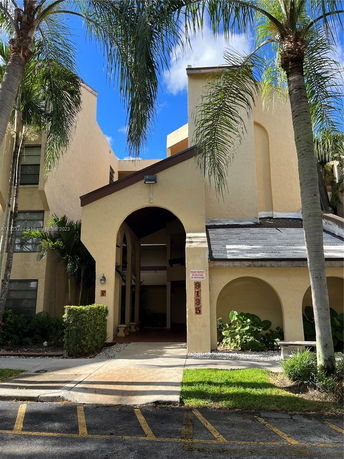Front view of a multi-story building with an arched entrance and beige exterior.