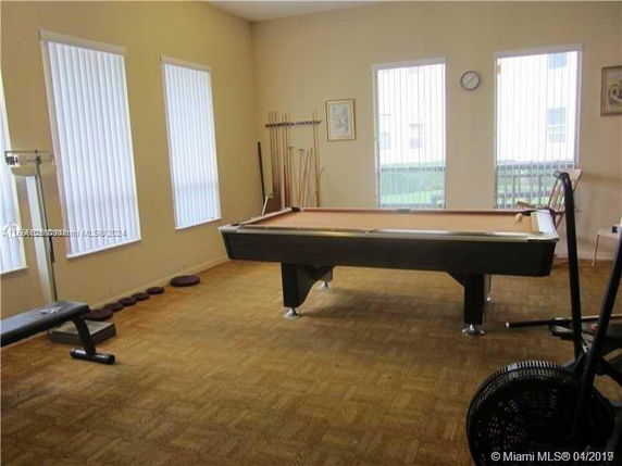 Room with a billiards table and exercise equipment.