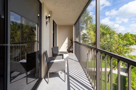 Balcony area with chairs and railing, overlooking greenery.