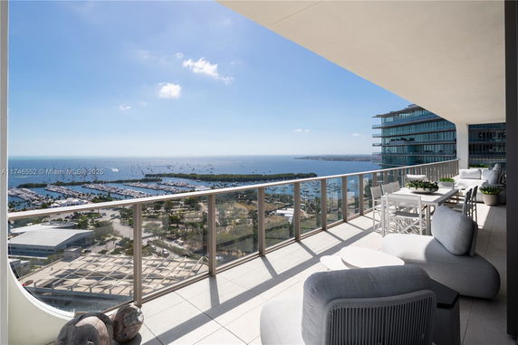 Wide angle view from a high-rise building's balcony overlooking a coastal area with boats and greenery.