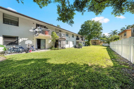 View of residential building with balconies and surrounding lawn area.