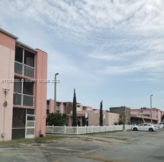 Front view of a multi-story residential building with balconies and a pink exterior.