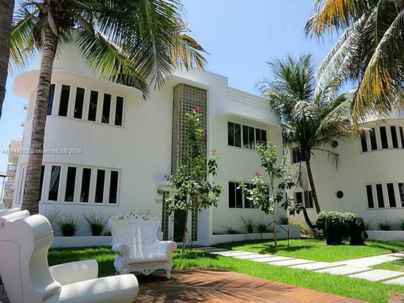Front view of a modern two-story house with large windows and palm trees.