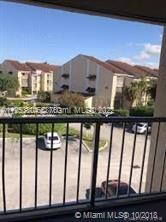 View from a balcony overlooking a parking area and residential buildings.
