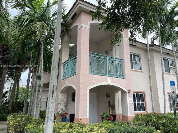 Front view of a two-story building with balconies and arched entrance.