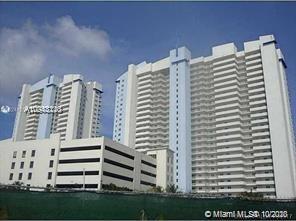 Front view of two high-rise residential buildings with multiple balconies and a connected parking structure.
