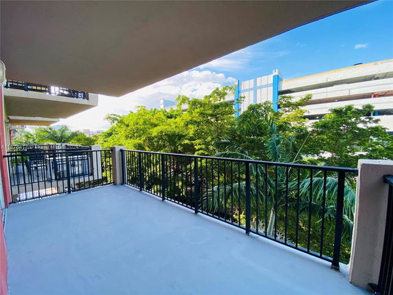 View from a balcony showing nearby trees and building structures.