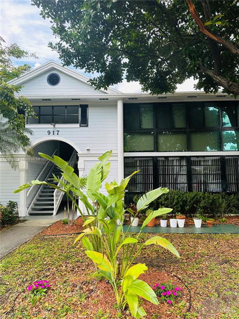 Front view of a two-story house with a staircase and plants in front.