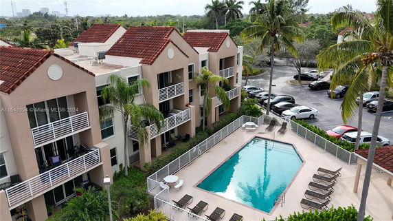 Swimming pool area adjacent to a multi-story residential building with balconies.