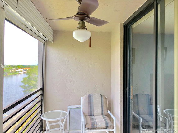 Balcony view with seating and ceiling fan overlooking a body of water.