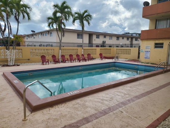 Outdoor swimming pool area with lounge chairs and surrounding buildings.