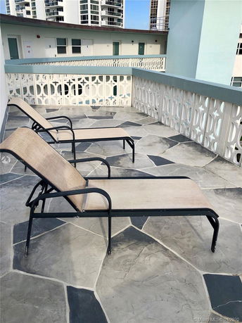 Rooftop area with lounge chairs and decorative railing.