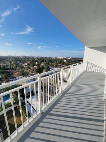 Balcony view from a building overlooking a residential area with clear blue sky.