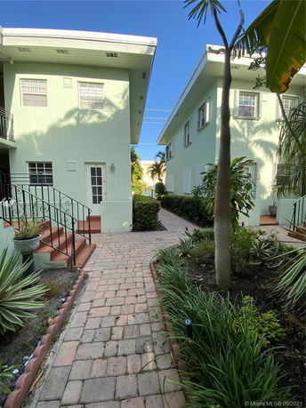 Front view of a two-story building with green exterior walls and a pathway.