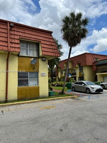 Front view of a two-story building with a red-tiled roof and yellow exterior walls.