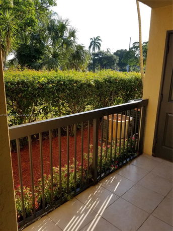 View from a balcony overlooking hedges and palm trees.
