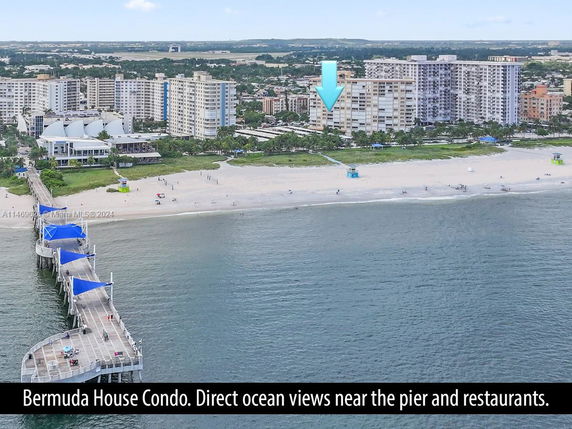 View of a beachside condominium complex near a pier and restaurants.