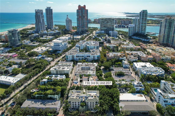 Aerial view of a coastal urban area with multiple mid-rise buildings and the ocean in the background.