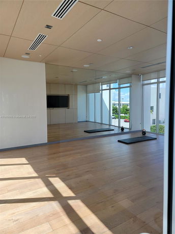 Room with wooden flooring, mirrored walls, and exercise equipment.