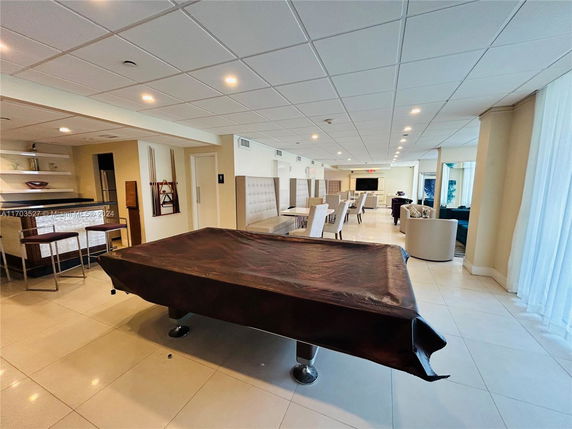 Interior view of a clubhouse with a covered pool table, seating area, and bar counter.