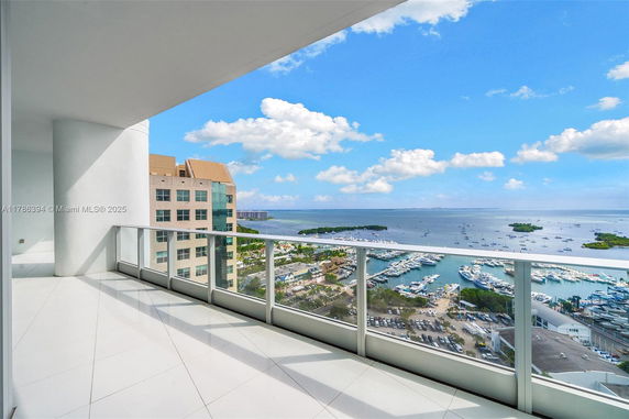 Panoramic view from a high-rise building balcony overlooking a marina and ocean.